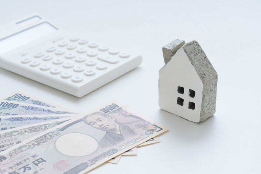 電卓とお金と白い家の模型