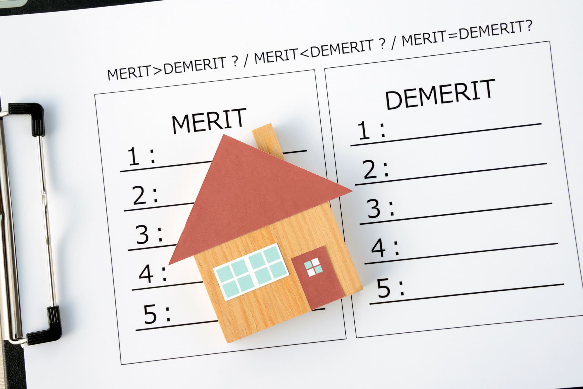 「MERIT」「DEMERIT」の比較が書かれた紙と家の模型
